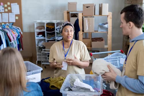 Hands holding a small paper house over a desk.